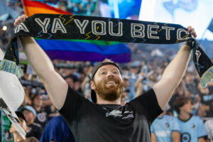 Jackson Smith holding a Dark Clouds scarf reading "YA YOU BETCHA" over his head